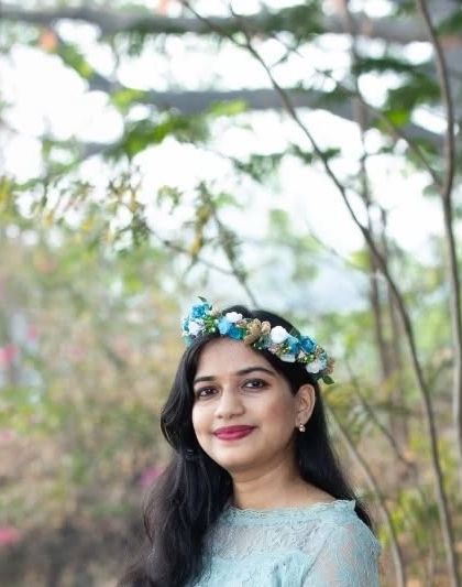 A beautiful close-up portrait with a blue and white floral crown. The soft, natural background keeps the focus on the mom-to-be's serene expression.