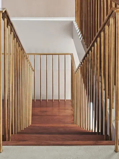 The vertical brass spindles of the railing create a rhythmic pattern, contrasting beautifully with the warm horizontal lines of the teak steps. This detail exemplifies our dedication to refined craftsmanship.