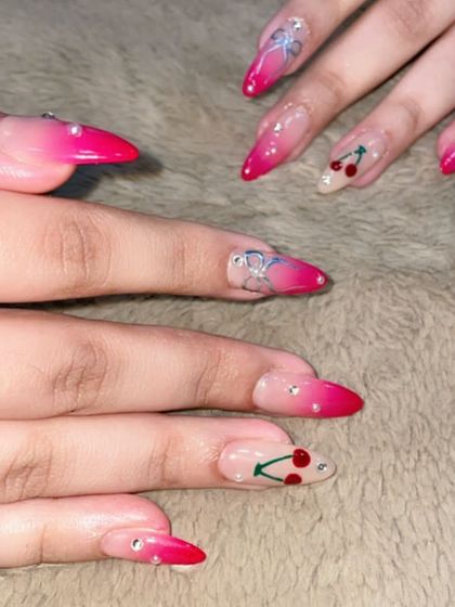 A fun and playful set perfect for a party. These long, stiletto nails feature a hot pink ombre, cherry art, and silver bow charms, all sparkling with tiny rhinestones.