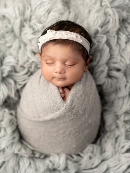 A perfectly swaddled newborn on a soft, fluffy grey blanket. This minimalist setup keeps the focus entirely on the baby.