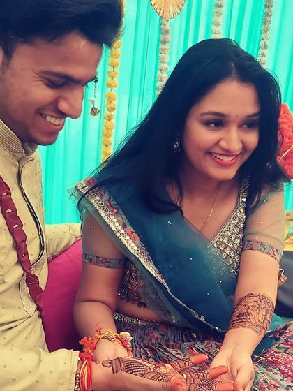 A happy moment captured during a mehndi ceremony. Our beautiful bride shows her intricate henna to the groom, a design filled with personal touches that celebrate their story.