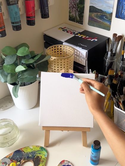 A shot of me starting the vibrant sunset painting in my studio, surrounded by my art supplies.