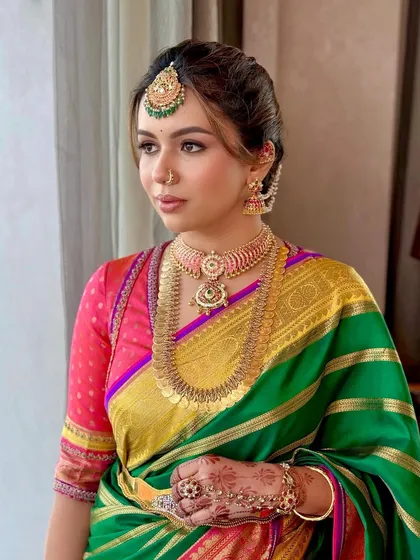 A three-quarter profile view highlighting the intricate hairstyle, maang tikka, and layered necklaces.
