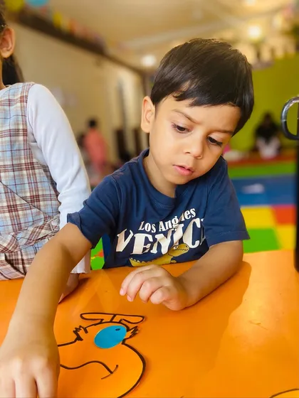 This student is focused on adding the final touches to his craft project at the table.