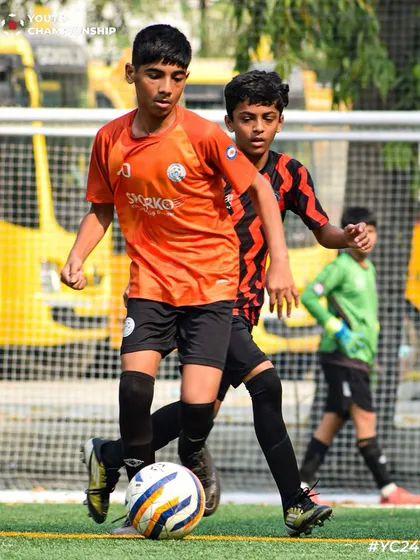 Eyes on the prize. A young attacker focused on moving the ball forward, with a defender in close pursuit.