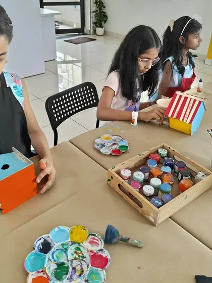 A group of girls focused on their birdhouse painting project. It's a great activity that combines painting with a bit of simple construction.