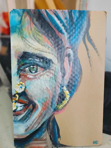 This is "Colors," an expressive portrait painted on repurposed cardboard. The side view shows the texture of the material and the vibrant, free brushstrokes.