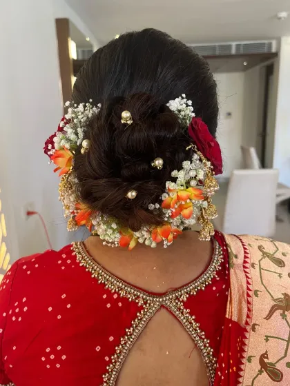 An elegant bridal bun for the mother of the groom, adorned with a mix of fresh flowers and pearls.