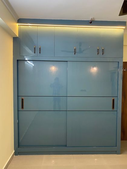 A large sliding wardrobe in a beautiful dusty blue color, complete with a loft for extra storage and sleek profile handles.