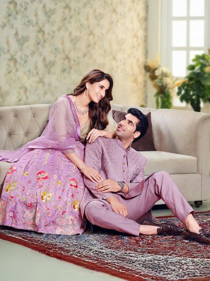 A soft and romantic look for a pre-wedding shoot or reception. The couple is styled in coordinating shades of lavender, with her in a floral lehenga and him in a subtly embroidered sherwani.