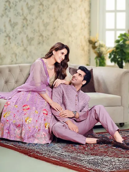 A soft and romantic look for a pre-wedding shoot or reception. The couple is styled in coordinating shades of lavender, with her in a floral lehenga and him in a subtly embroidered sherwani.