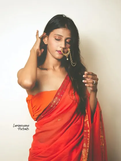 A soft and sensual portrait, with the model's hair partially covering her face as she adjusts her nath.