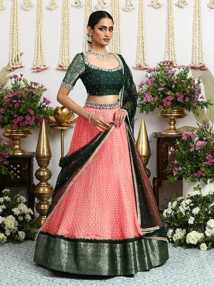 The full, standing view of the coral and green lehenga, a perfect outfit for a summer wedding.