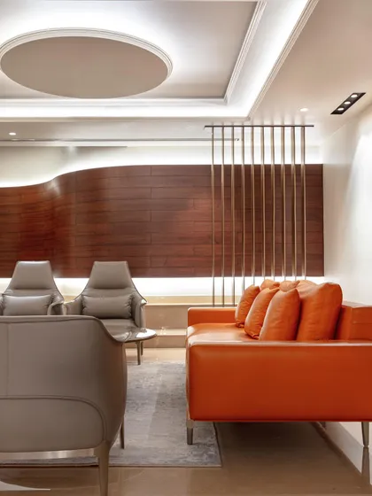 In the Wanderlust Villa, this modern lounge area features a bold orange sofa and a sculptural curved wood wall. It's a contemporary space designed for relaxation and conversation.