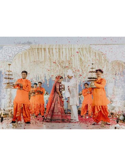 The grandeur of Eesha and Tarun's Varmala ceremony, with attendants in vibrant orange creating a stunning visual frame.