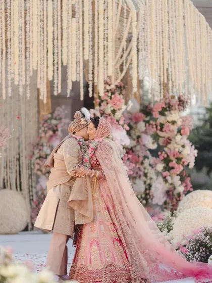 A kiss that seals their forever, surrounded by a cloud of pastel florals. I designed this mandap with cascading white flowers and soft pink roses to create a truly romantic and dreamy setting for their vows.