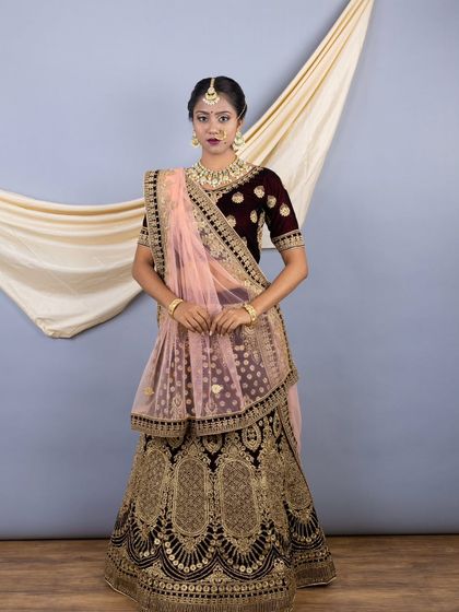 A beautiful deep wine velvet lehenga, perfect for a bride. The heavy gold zari embroidery gives it a very royal and traditional feel, and the contrasting light pink dupatta adds a touch of softness.