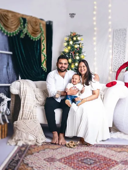 A happy family of three, all dressed in white, enjoying the festive ambiance of our Christmas studio.