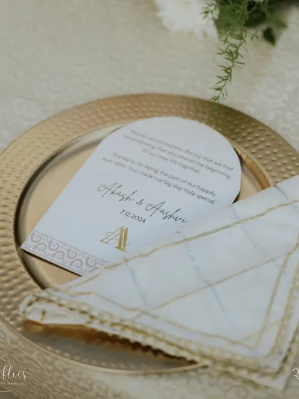 A personalized thank you note and monogrammed place setting for Aashvi and Akash's wedding. The elegant gold and ivory design matched the timeless theme of their ceremony.
