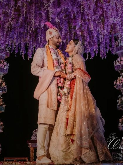 Under a canopy of cascading purple wisteria, the bride and groom share an intimate gaze. This is the kind of romantic, fairytale atmosphere we specialize in creating.