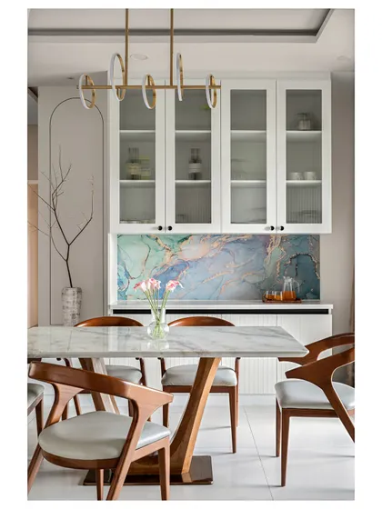 This dining area features a stunning blue marble-finish laminate backsplash, which provides the luxurious look of real stone at a more accessible price point. Paired with elegant wooden chairs and a modern pendant light, it creates a space that is both artistic and functional.