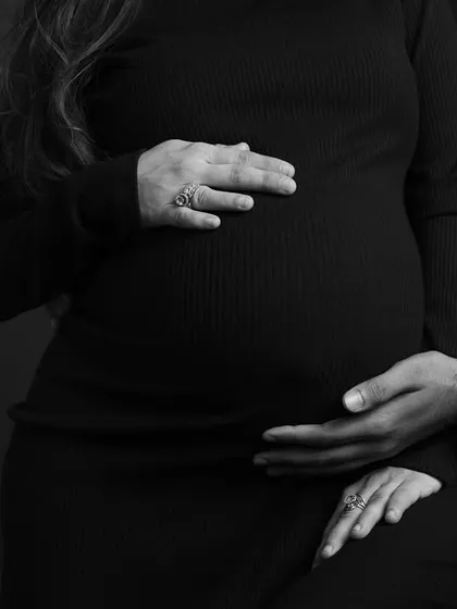 A close-up on the hands and the bump. This simple, focused black and white shot tells a powerful story of connection and anticipation.
