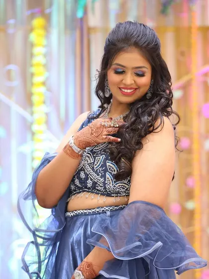 This candid shot captures the joy of the moment. The client's makeup features a subtle blue shimmer on the eyes to match her outfit, paired with a radiant smile.