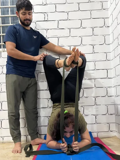 To achieve the perfect form, we often use props like yoga straps. I provide careful guidance to ensure every student can safely explore advanced postures like this supported inversion.