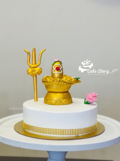 A divine Mahashivratri special cake. This elegant white cake is topped with a golden, fully edible Shivling and Trishul, which can be removed before cutting.
