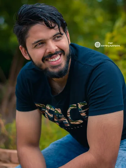 A classic candid portrait of a man smiling. The focus is on capturing a relaxed and happy moment in a natural outdoor setting.