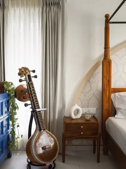 We believe a home should reflect the personality of its owners. In this bedroom, a traditional four-poster bed and a cherished musical instrument, the veena, are given pride of place, creating a space that is deeply personal and rooted in culture.