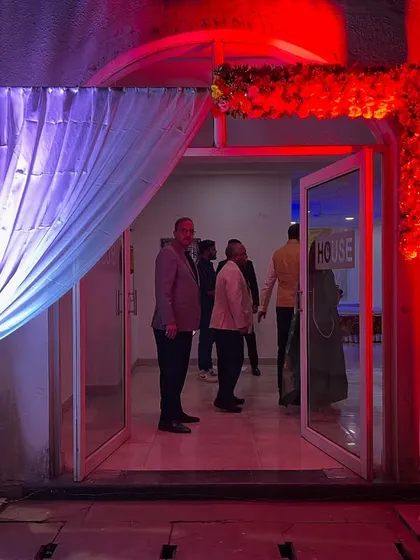 A simple yet elegant entrance for an evening event, using white drapes, floral accents, and dramatic red lighting.