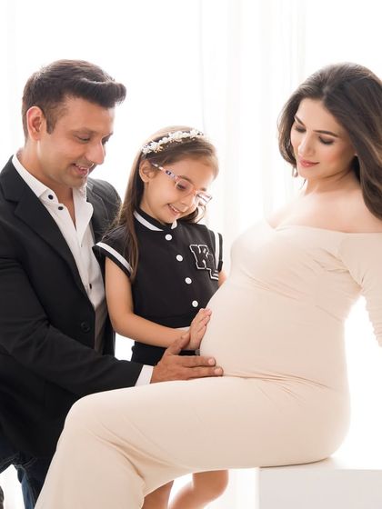 The whole family shares a moment of connection with the baby bump. It's a beautiful portrait of anticipation and shared love.
