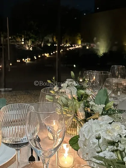 An evening view of a beautifully set table, with the garden lights twinkling in the background. The glassware sparkles in the candlelight, promising a magical dinner.