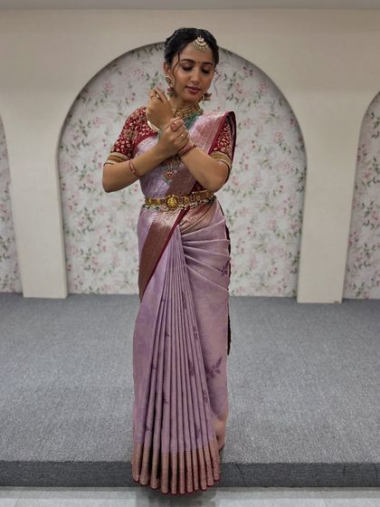 A full-length shot of a model in a lavender silk saree. The pleats are kept crisp and uniform, and the pallu is draped neatly to create a sophisticated and modern ethnic look.