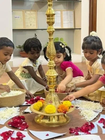 Children dressed in traditional attire carefully arrange flower petals to create a beautiful Pookalam for Onam. This hands-on cultural activity teaches them about traditions, aesthetics, and the joy of creating together.