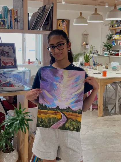 A proud artist showing her stunning landscape painting with a dramatic, colorful sky. Our mentors are always there to help kids tackle tricky parts and cheer them on.