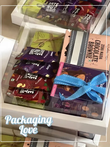 Packaging love! This clear-lid box shows off all the delicious treats inside, while the blue ribbon adds a pop of color that matches the birthday theme.