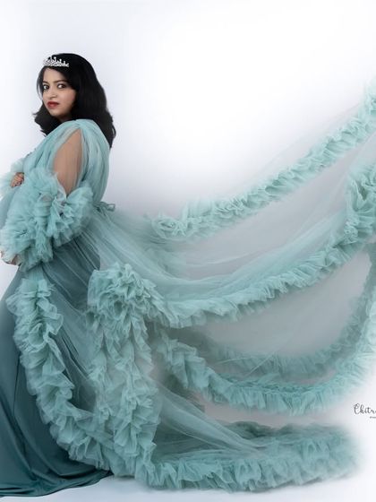 A profile shot that emphasizes the beautiful train of this sea-green ruffled gown. The simple white background keeps all the focus on the mom-to-be.