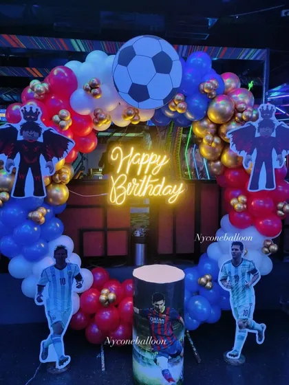 For the ultimate football fan, I created this Messi-themed birthday decoration. The setup includes a balloon ring in team colors, a 'Happy Birthday' neon sign, and multiple cutouts of the football star in action.
