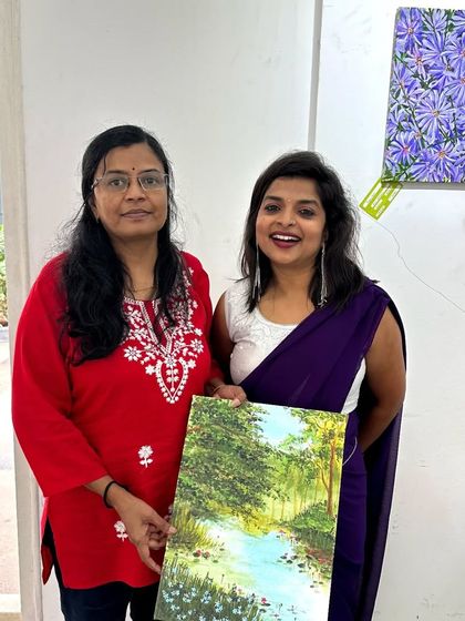 With a fellow artist at an exhibition, holding one of my landscape paintings.
