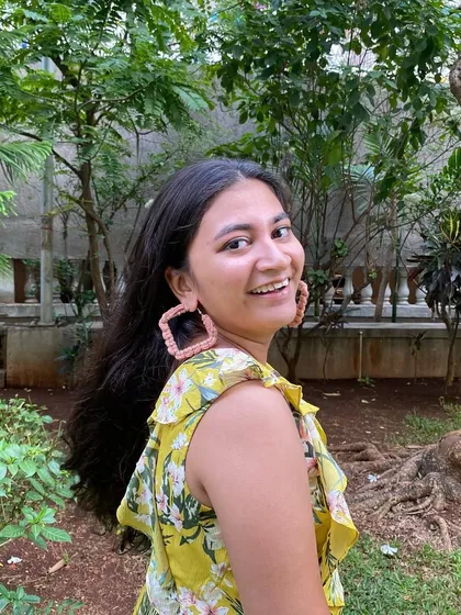 A smiling model wearing our square macrame earrings. They are a great example of our wearable art, combining modern design with traditional macrame techniques.