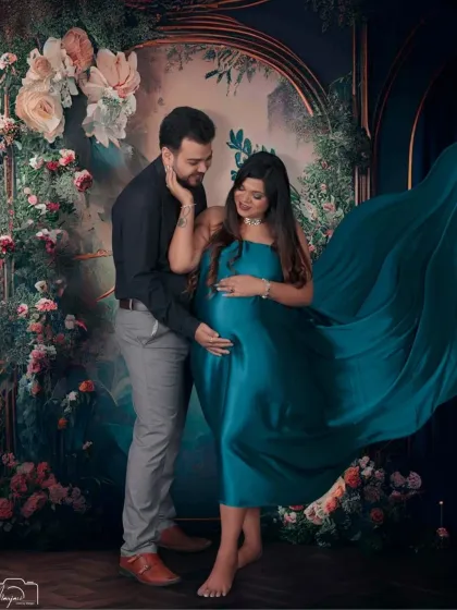 A beautiful and artistic shot with the flowing teal fabric creating a dramatic wing-like effect against a floral backdrop.