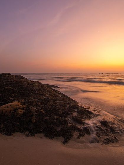 A duplicate of image 85, a simple and beautiful long exposure of a beach rock at sunset, focusing on the warm colors and soft textures.