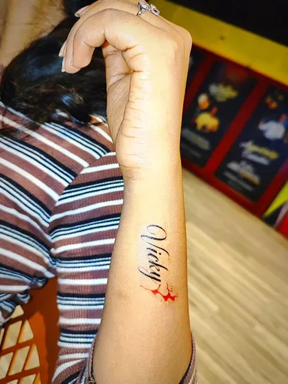 Here is another example of a custom name tattoo, this time in an elegant cursive font with a small color accent. We can personalize your temporary tattoo with different styles and small graphic elements to make it truly yours.
