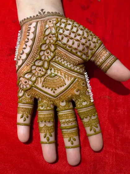 A lovely back-hand design with delicate floral and jhumka details, showing the fresh green color of the natural henna paste.