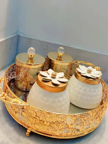 A beautiful set of four decorative jars, perfect for filling with treats, placed in an elegant golden tray with a mirrored base.