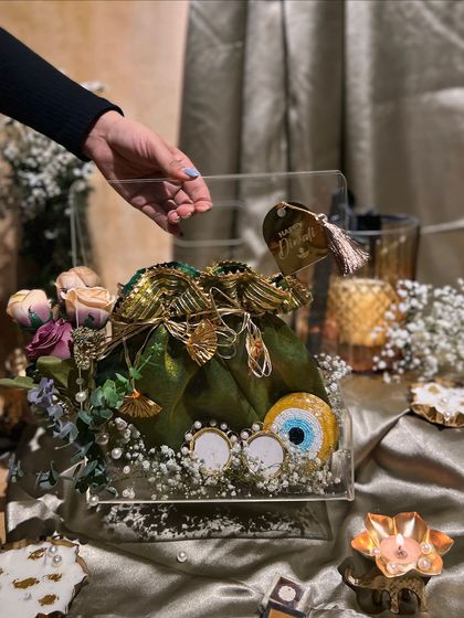 Holding up the acrylic bag Diwali hamper. The clear design allows the beautiful green potli and its contents to be the star of the show.