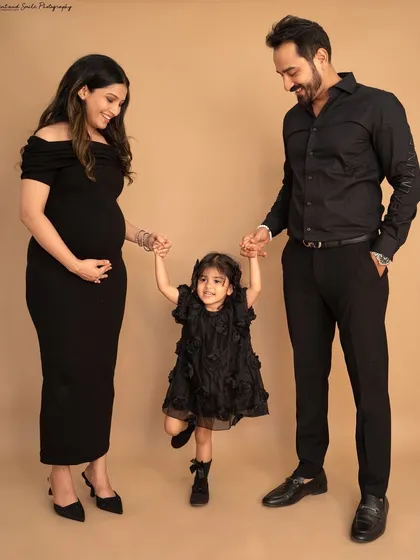 A playful moment during a studio maternity shoot. Holding hands and swinging their daughter, this photo perfectly captures the fun and happiness of this growing family.