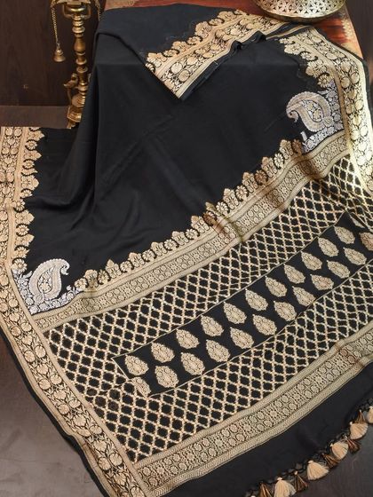 A classic black georgette saree with intricate gold weaving in traditional motifs. This is a sophisticated and timeless party saree that exudes elegance.